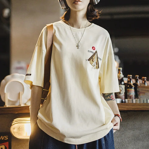 Person wearing a beige t-shirt with a graphic design in an indoor setting